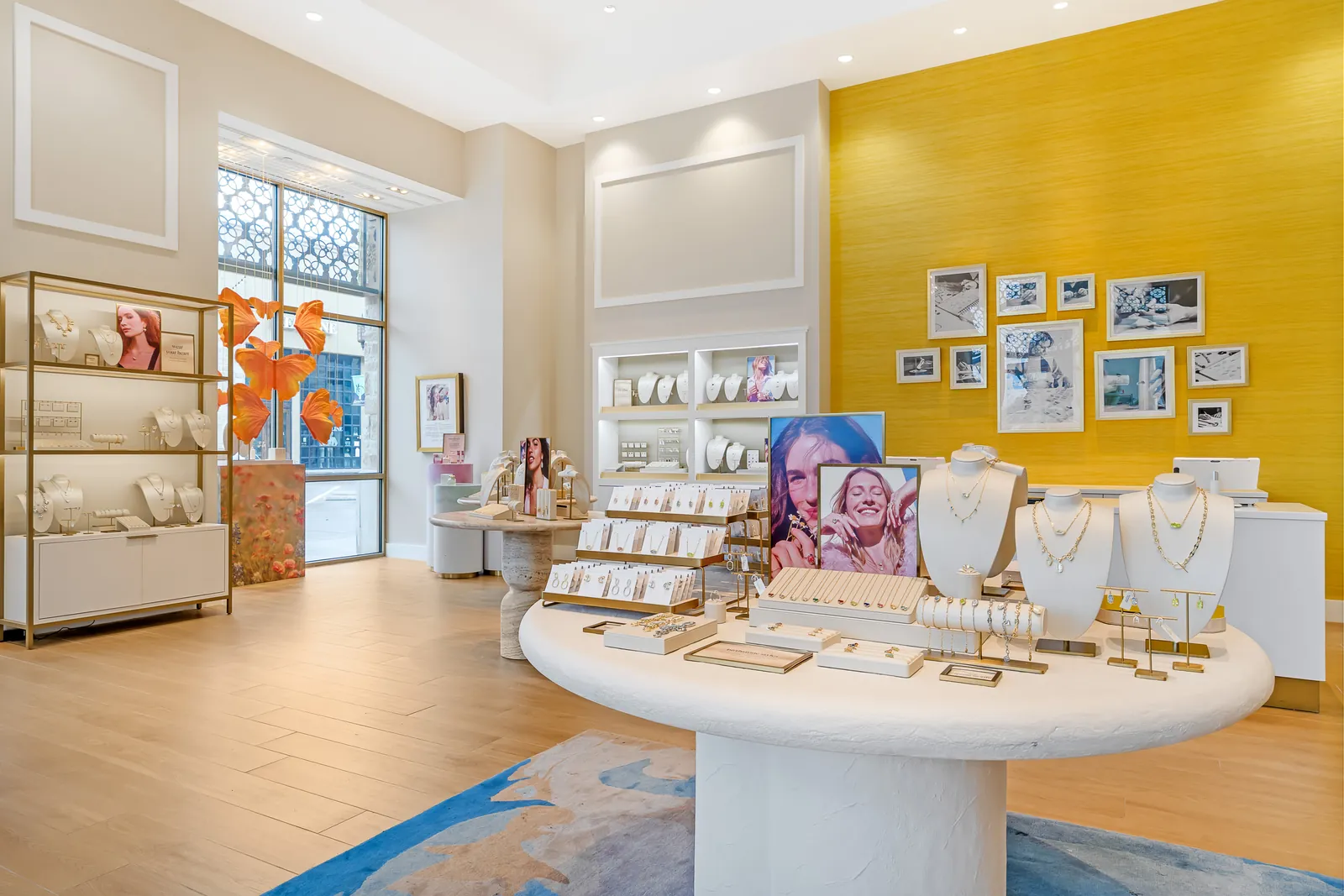 Kendra Scott sales floor — display table and feature wall with framed gallery